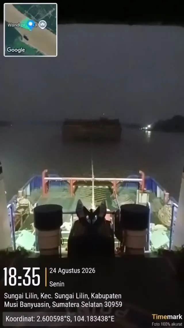 Tongkang ditarik pada malam hari dilihat dari buritan kapal tunda di Sungai Lilin
