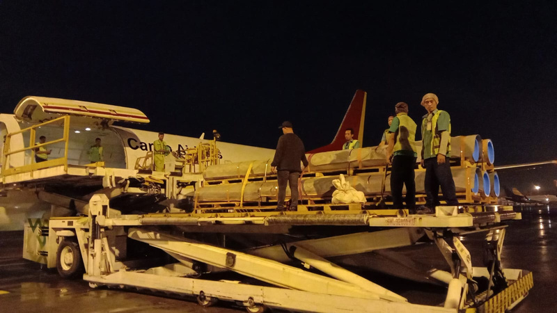 Tim kargo menyiapkan muatan industri di samping pesawat kargo